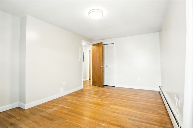 unfurnished room with baseboards, baseboard heating, and light wood-style floors