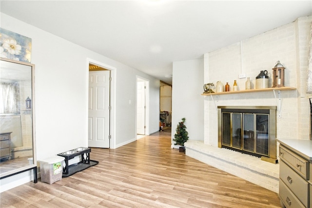 living area featuring light wood-type flooring, a fireplace, and baseboards