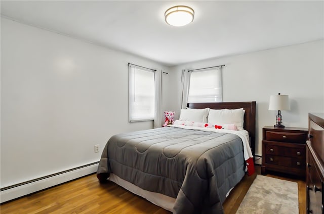 bedroom featuring a baseboard heating unit and wood finished floors