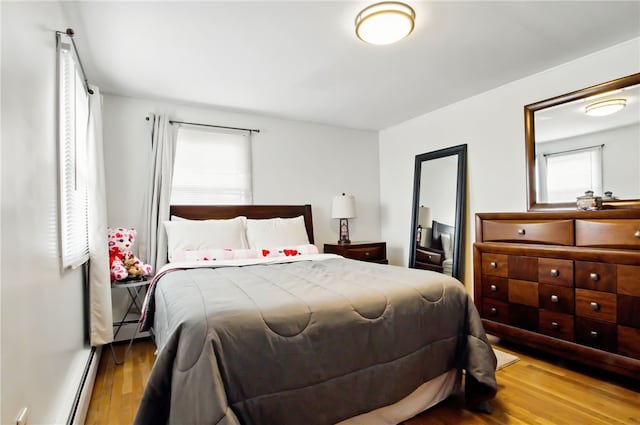 bedroom featuring a baseboard heating unit and wood finished floors