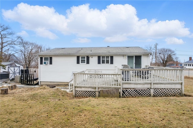 rear view of house featuring an outbuilding, a yard, a wooden deck, and a storage shed