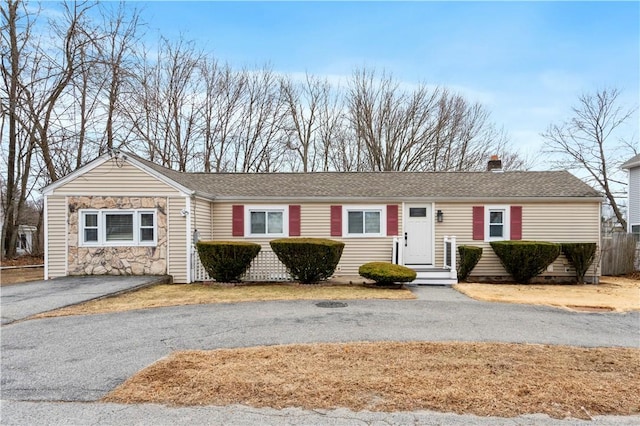 single story home featuring crawl space, stone siding, driveway, and roof with shingles