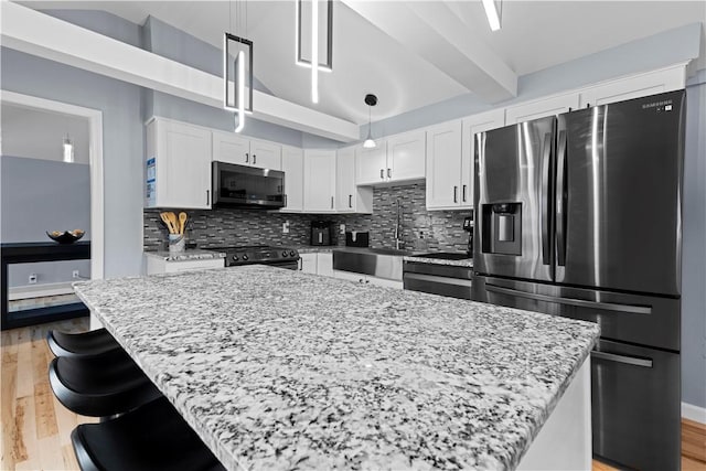 kitchen featuring black range with electric stovetop, decorative backsplash, white cabinetry, a sink, and stainless steel fridge with ice dispenser