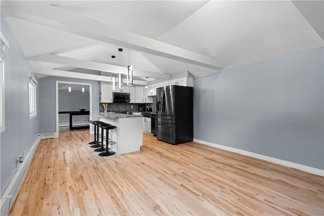 kitchen with tasteful backsplash, white cabinets, a breakfast bar, stainless steel appliances, and light wood-type flooring