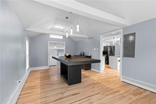 kitchen featuring electric panel, lofted ceiling, a kitchen island, fridge with ice dispenser, and light wood-style floors