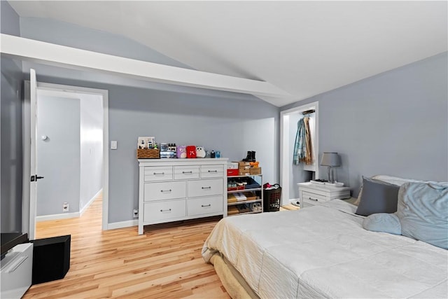 bedroom with light wood-style floors, lofted ceiling, and baseboards