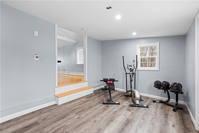 exercise room featuring baseboards, wood finished floors, and recessed lighting