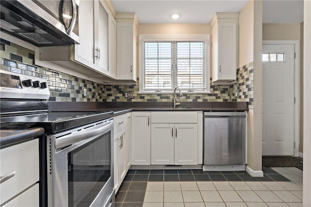 kitchen with light tile patterned floors, appliances with stainless steel finishes, dark countertops, and a sink