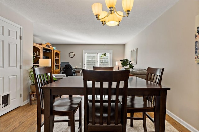 dining room featuring a chandelier, a textured ceiling, baseboards, and light wood-style floors