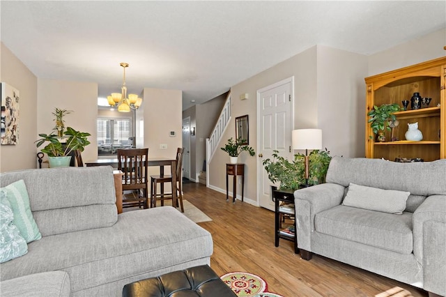 living area featuring stairs, light wood finished floors, baseboards, and an inviting chandelier