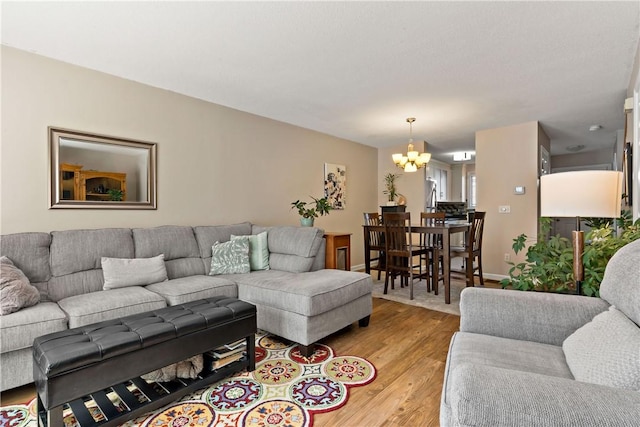 living room with a chandelier, baseboards, and light wood finished floors