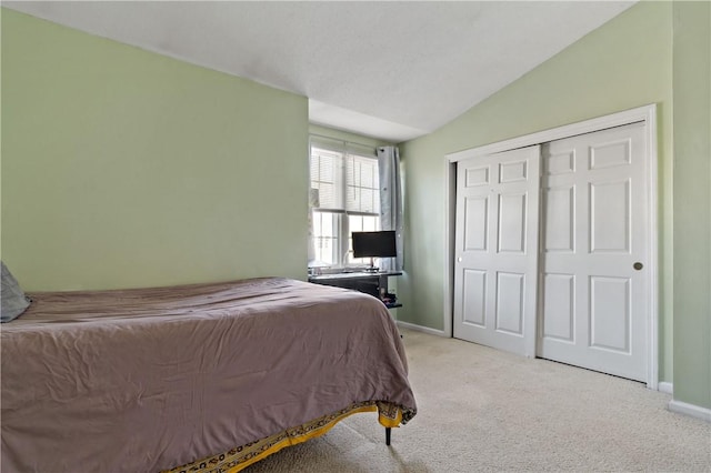 carpeted bedroom with lofted ceiling, a closet, and baseboards