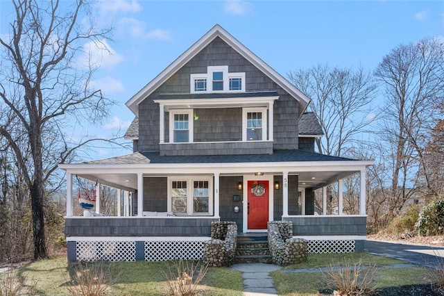 view of front of home with a porch, a front yard, and a shingled roof