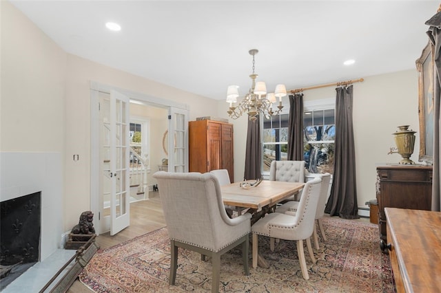 dining area featuring a fireplace, a chandelier, a wealth of natural light, and french doors