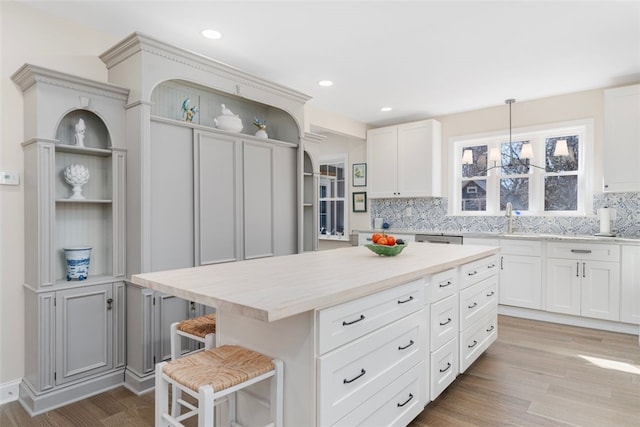 kitchen with a breakfast bar area, light countertops, light wood-type flooring, backsplash, and open shelves