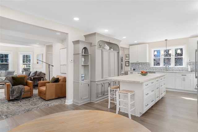 kitchen with a breakfast bar area, a center island, light countertops, open shelves, and backsplash