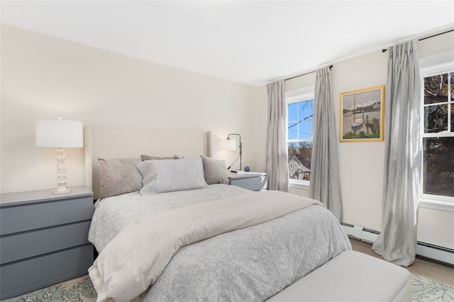 bedroom with a baseboard radiator and wood finished floors