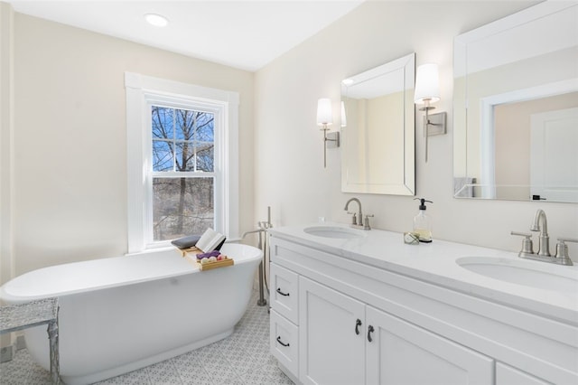 bathroom featuring a freestanding bath, double vanity, a sink, and recessed lighting