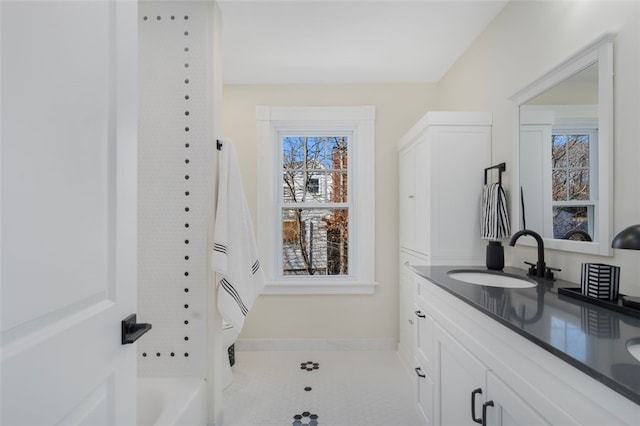 full bath featuring double vanity, a sink, and baseboards