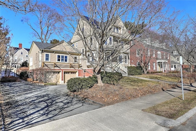 view of front of property with a garage, aphalt driveway, brick siding, and a residential view