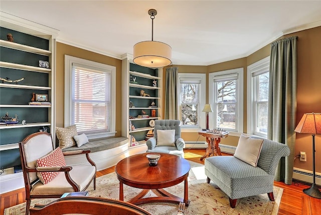 living area featuring a baseboard heating unit, crown molding, baseboards, and wood finished floors