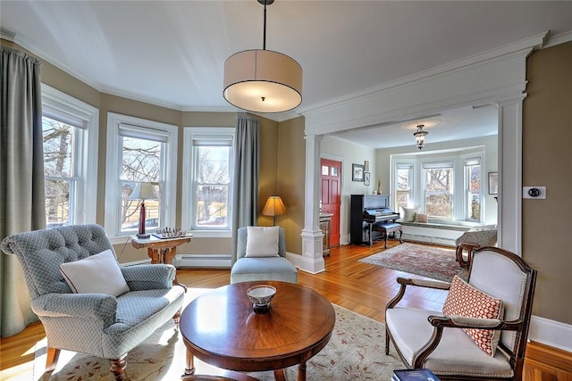 sitting room with ornamental molding, a wealth of natural light, a baseboard heating unit, and ornate columns