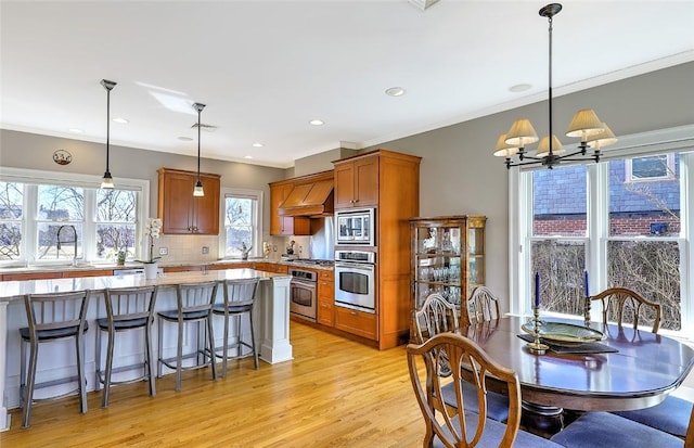 kitchen with brown cabinets, stainless steel appliances, tasteful backsplash, custom range hood, and light wood-type flooring