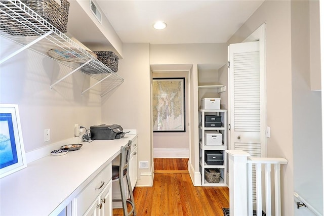 spacious closet featuring light wood-style flooring, visible vents, and built in desk