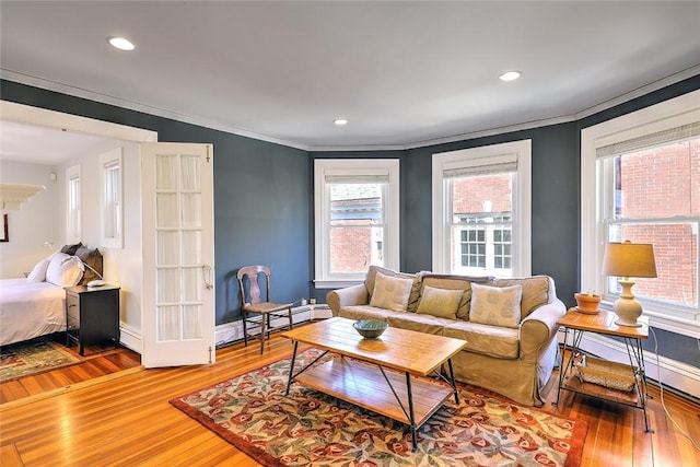 living room with baseboards, crown molding, light wood-type flooring, a baseboard heating unit, and recessed lighting