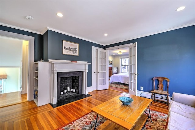 living area featuring a fireplace with flush hearth, french doors, wood finished floors, and ornamental molding