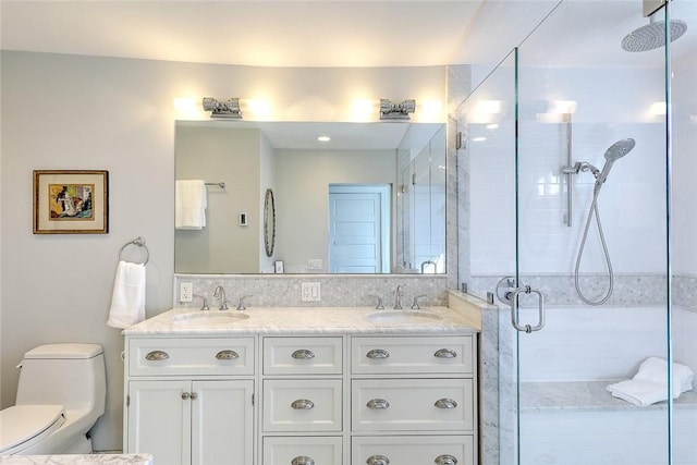 full bath with double vanity, a stall shower, a sink, and toilet