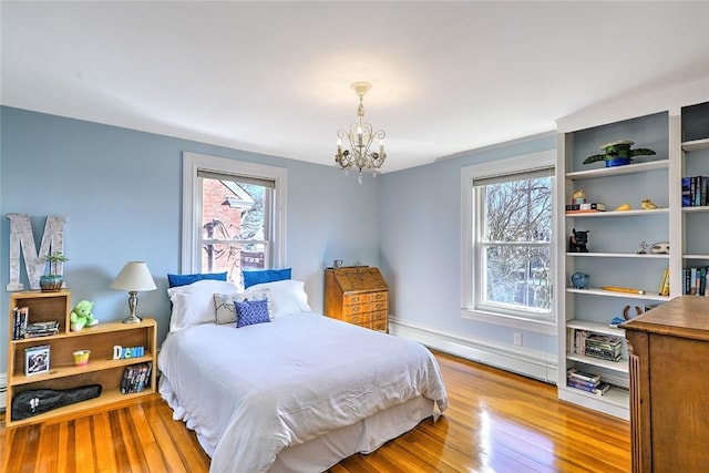 bedroom with a chandelier, baseboard heating, and wood finished floors