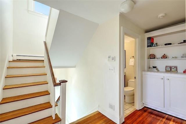 stairs with a baseboard heating unit, a skylight, visible vents, and wood finished floors