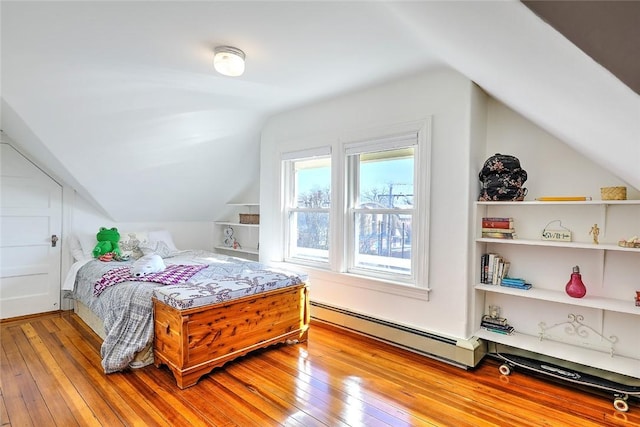 bedroom featuring a baseboard heating unit, vaulted ceiling, and light wood-type flooring