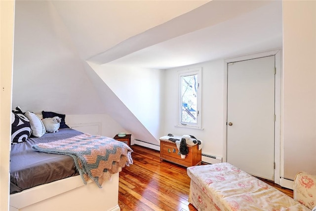 bedroom featuring a baseboard heating unit, wood-type flooring, and a baseboard radiator