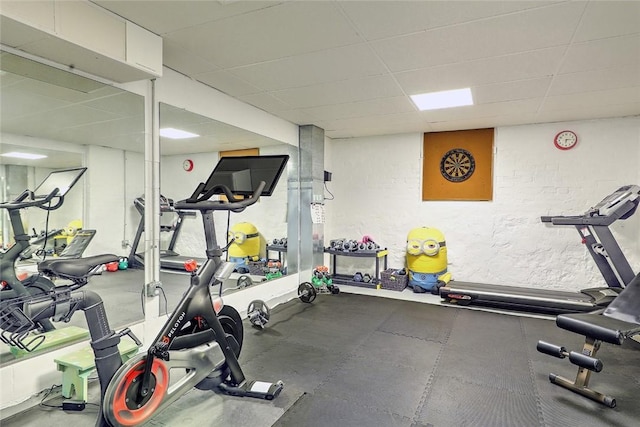 exercise area featuring a textured wall and a drop ceiling