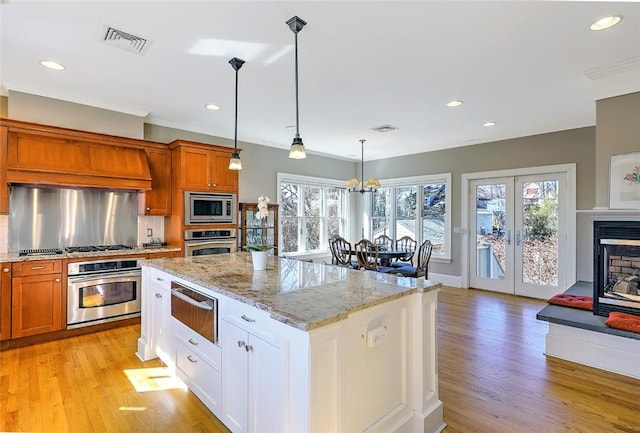 kitchen with light stone countertops, stainless steel appliances, visible vents, decorative backsplash, and a warming drawer