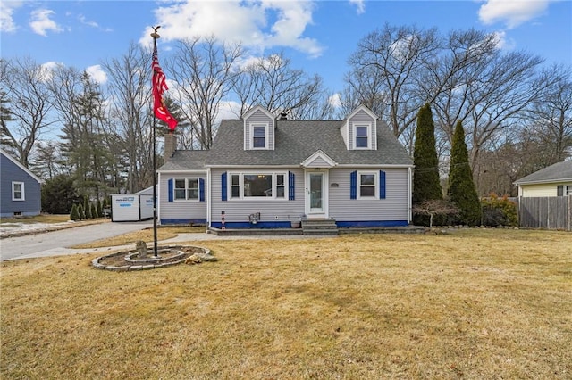 new england style home featuring entry steps, a front lawn, a shingled roof, and fence