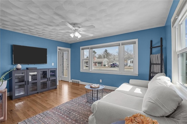 living room featuring visible vents, ceiling fan, baseboards, and hardwood / wood-style flooring