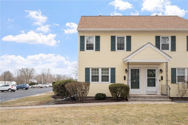 view of front of property with a shingled roof and a front yard