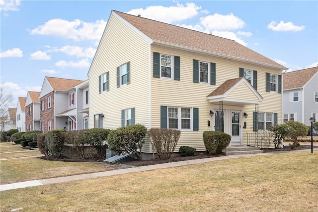 colonial home with a shingled roof and a front yard