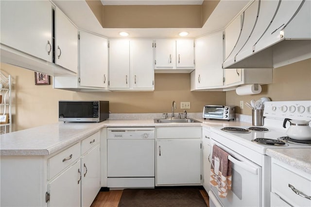 kitchen featuring under cabinet range hood, white appliances, a sink, white cabinets, and light countertops