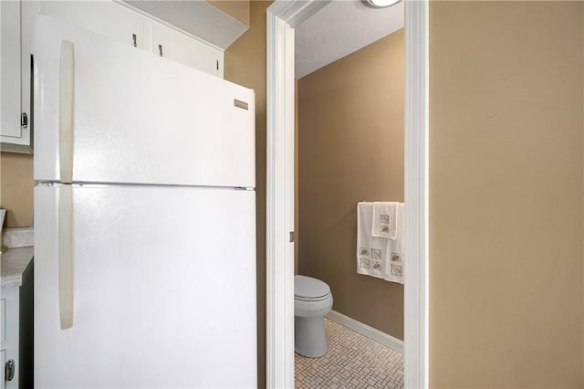 bathroom featuring tile patterned flooring, toilet, and baseboards