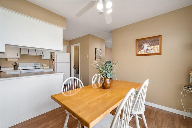 dining space featuring light wood-style floors, baseboards, and a ceiling fan