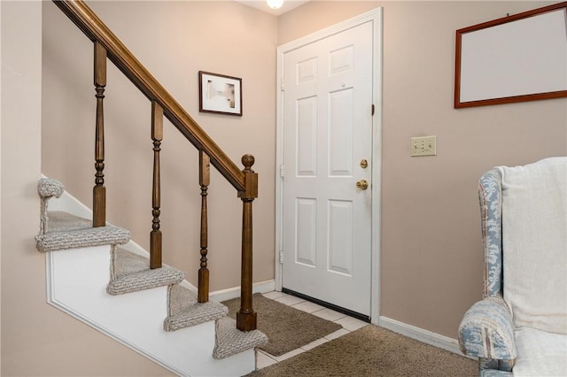 entryway featuring light tile patterned floors, stairs, and baseboards