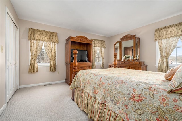 bedroom with light carpet, multiple windows, baseboards, and a closet