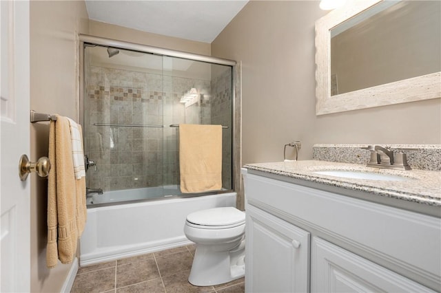 bathroom featuring tile patterned flooring, combined bath / shower with glass door, vanity, and toilet