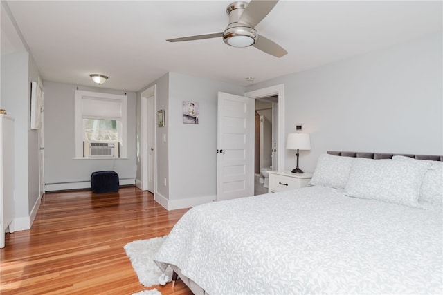 bedroom featuring light wood finished floors, a baseboard radiator, baseboards, and cooling unit