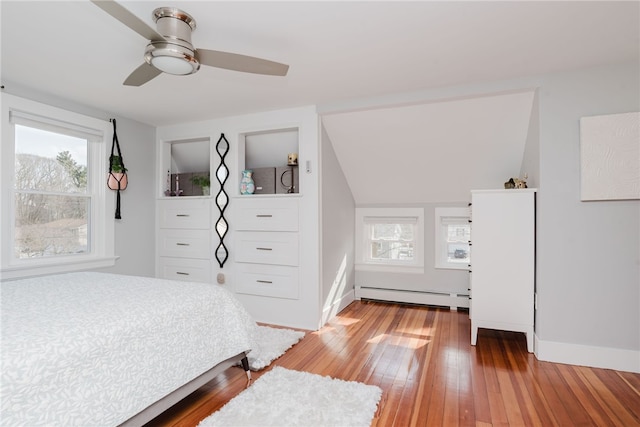 bedroom featuring a baseboard heating unit, baseboards, a ceiling fan, and light wood-style floors