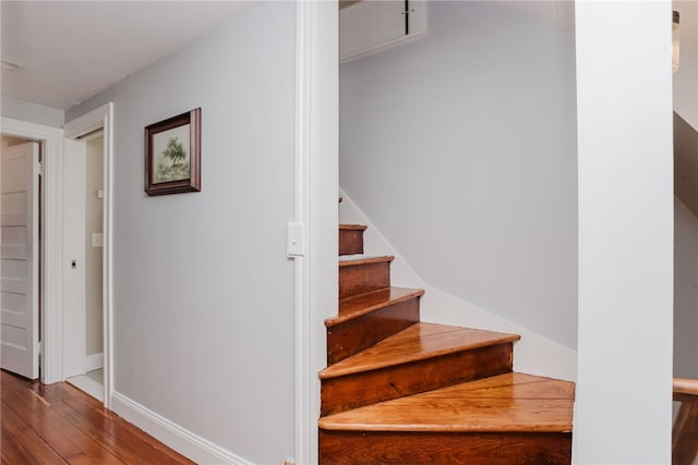 staircase featuring wood finished floors and baseboards